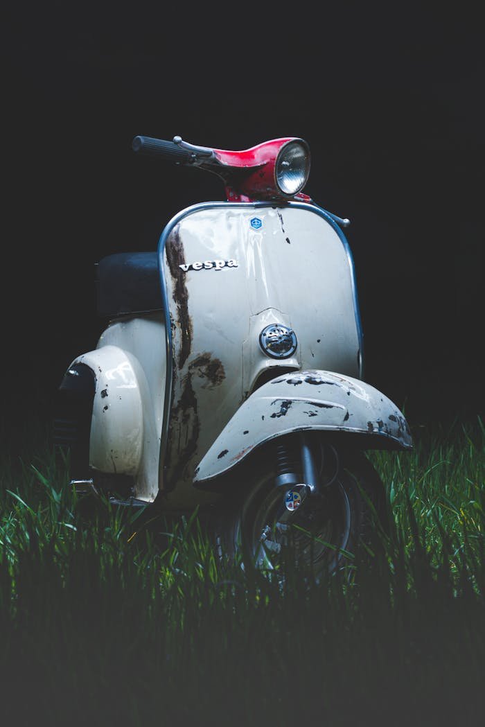 Classic Vespa scooter parked outdoors in grass, showcasing retro style in Athens.